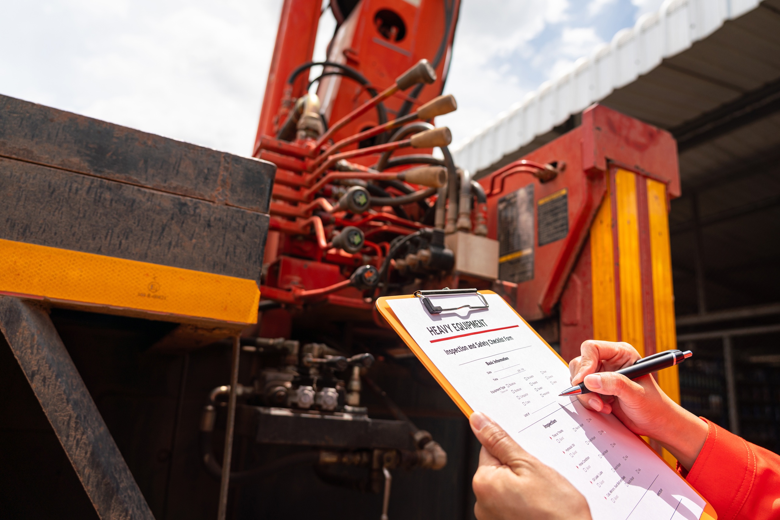 A mechanical engineer is inspecting the condition of truck crane vehicle (as blurred background) before start the operation on the inspection checklist form. Industrial working with safety practice.